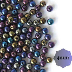 Op de afbeelding: Een close-up afbeelding van een stapel iriserende glazen kralen. De kralen zijn 4 mm in diameter en hebben een metallic afwerking. De kleuren van de kralen zijn blauw, groen, goud en paars.
