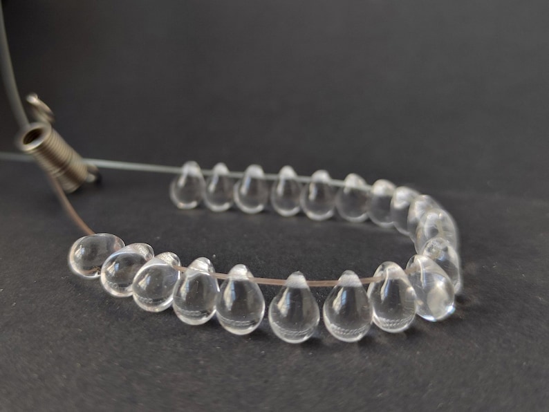 May include: A strand of clear teardrop-shaped beads strung on a thin wire.