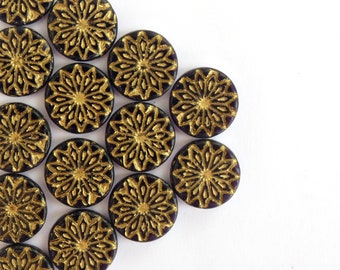 May include: A group of round, black glass buttons with gold floral designs. The buttons are arranged in a triangular pattern on a white background.