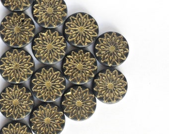 May include: Black and gold round buttons with a floral design. The buttons are arranged in a triangular pattern.