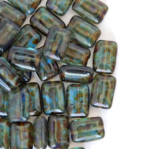 May include: A pile of iridescent glass beads in shades of teal, brown, and green. The beads are rectangular and have a mottled, textured surface.
