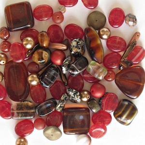 Puede incluir: Surtido de cuentas de vidrio de color rojo, marrón y dorado en varias formas y tamaños. Las cuentas son perfectas para hacer joyas o manualidades.