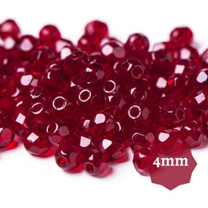 Może przedstawiać: Stosik czerwonych szklanych koralików o średnicy 4 mm. Korale są fasetowane i mają błyszczące wykończenie.