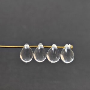 May include: Four clear glass teardrop beads strung on a gold wire.