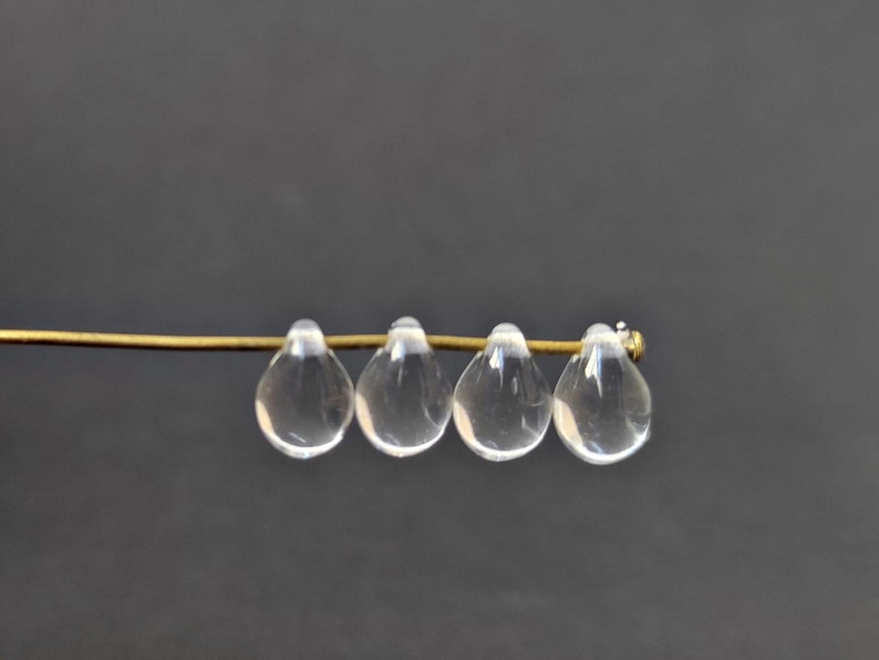 May include: Four clear glass teardrop beads strung on a gold wire.