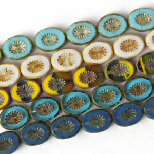 May include: A strand of oval-shaped glass beads with a variety of colors and patterns, including blue, yellow, white, and brown. The beads have a raised, decorative design in the center.