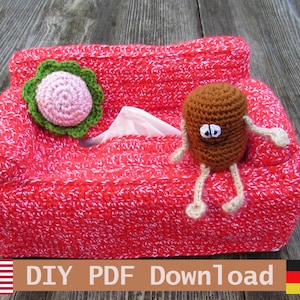 Könnte beinhalten: Eine handgefertigte rot-weiß gehäkelte Taschentuchbox-Abdeckung mit einer dekorativen Blume und einem braunen gehäkelten Charakter mit Armen und Beinen. Der Text "DIY PDF Download" ist sichtbar.