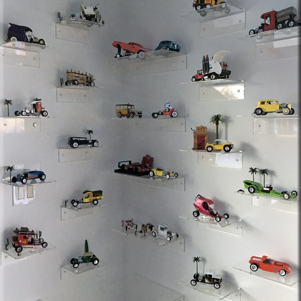 Peut inclure: Une collection de voitures miniatures vintage exposées sur des étagères en acrylique transparentes. Les voitures sont de différentes couleurs et styles, notamment une voiture de course rouge, un bus scolaire jaune et un pick-up vert.