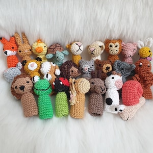 Könnte beinhalten: Eine Sammlung von 24 gehäkelten Fingerpuppen mit verschiedenen Tieren, darunter ein Löwe, ein Frosch, eine Schildkröte, eine Katze, ein Pferd, eine Kuh und eine Schnecke. Die Puppen sind aus buntem Garn gefertigt und haben detaillierte Merkmale.