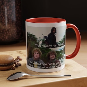 May include: A white ceramic mug with a bright red interior and handle. The exterior features a printed scene with three characters and the text: "You already had coffee." and "We've had one coffee, yes. What about second coffee?" in white lettering.