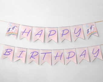 May include: A pink and purple banner that says "HAPPY BIRTHDAY". The banner has a watercolor effect and features a unicorn with a rainbow and moon on each end. The banner is strung on a thin, natural-colored string.