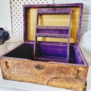 Könnte beinhalten: Eine antike Holzkästchen für Schmuck mit einem violetten Samt-Innenraum und einem Messingverschluss. Die Box hat ein herausnehmbares Fach mit Fächern zur Aufbewahrung von Schmuck.