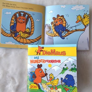 Könnte beinhalten: Ein Kinderbuch mit farbenfrohen Illustrationen. Das Cover zeigt eine Cartoon-Maus, Ente und Elefant mit dem Titel "Die Maus Das Wunderfernrohr". Die Innenseiten zeigen die Maus und ihre Freunde in verschiedenen Szenen. Das Buch ist ein Pixi Buch.