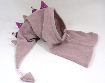 May include: A pink fleece hooded hat with a purple and white patterned tail and spikes. The hat has a drawstring closure.