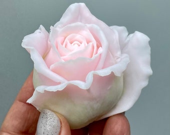 May include: A delicate, light pink rose crafted from soap. The rose is fully bloomed and has a soft, rounded shape.