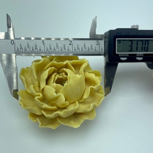 Pode incluir: Uma flor artificial de cor amarelo claro que se assemelha a uma pe&oacute;nia, com um di&acirc;metro de 8,05 cm. A flor &eacute; feita de um material liso e ceroso e tem um aspeto realista.