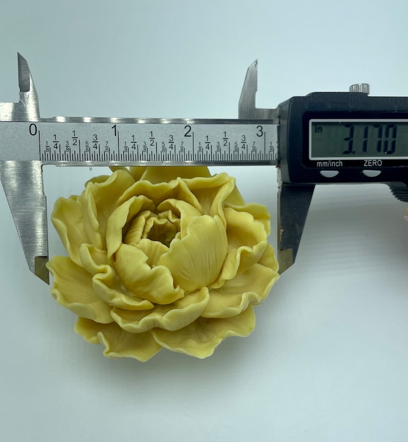 Pode incluir: Uma flor artificial de cor amarelo claro que se assemelha a uma pe&oacute;nia, com um di&acirc;metro de 8,05 cm. A flor &eacute; feita de um material liso e ceroso e tem um aspeto realista.