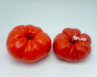 May include: Two vibrant red decorative pumpkins. The larger pumpkin is round with deep ridges and a dark center. The smaller pumpkin has a white, curly stem. Both are set against a white background.