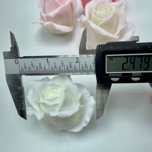 Pu&ograve; includere: Una rosa di tessuto bianco misurata con un calibro, che mostra una misura di 2,79 pollici.