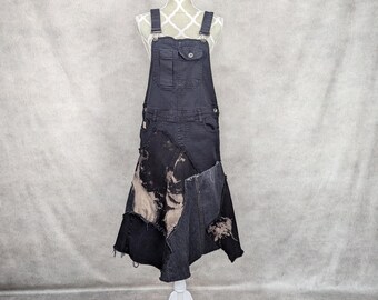 May include: Black denim overall dress with a patchwork skirt and distressed details. The skirt is asymmetrical and features a variety of denim fabrics.
