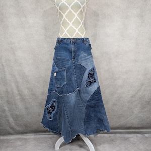 Puede incluir: Una falda larga de mezclilla hecha de mezclilla de retazos con bordes deshilachados y costuras decorativas. La falda es de color azul oscuro y tiene una variedad de texturas de mezclilla diferentes.