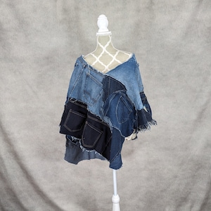 Peut inclure: Un poncho en jean fait de jeans recyclés. Le poncho est un patchwork de différentes nuances de denim bleu et a un bord effiloché.