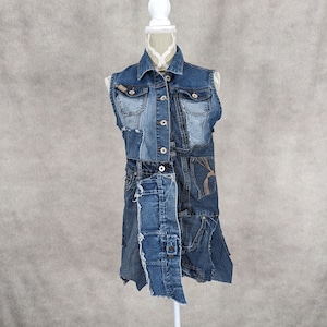 Könnte beinhalten: Eine ärmellose Jeansweste aus recyceltem Jeansstoff. Die Weste hat einen Knopverschluss vorne und mehrere Taschen. Die Weste wird auf einer weißen Schaufensterpuppe präsentiert.