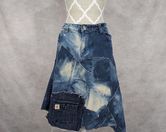 May include: A blue denim skirt with a patchwork design. The skirt is asymmetrical and has a frayed hem. The skirt has a large pocket on the side.