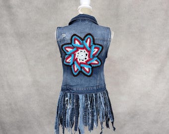 May include: A denim vest with a crocheted flower design on the back. The vest has a frayed hem and is sleeveless.