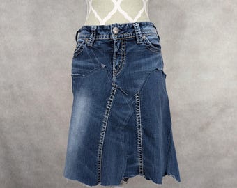 May include: A blue denim skirt with a frayed hem and a patchwork design. The skirt has a high waist and a fitted silhouette.