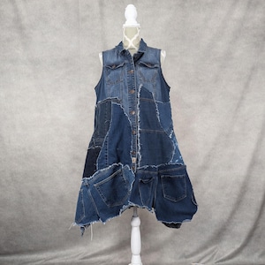 May include: A denim vest made from repurposed denim fabric. The vest has a patchwork design with different shades of blue denim. The vest has a collar and button closure. The vest is sleeveless and has a loose fit.
