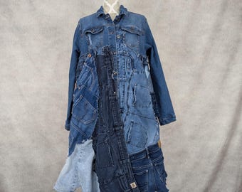 May include: A long denim coat made from repurposed denim fabric. The coat has a patchwork design with different shades of blue denim. The coat is on a white mannequin.