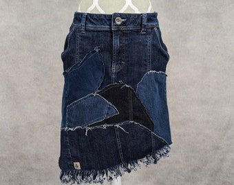 May include: A dark blue denim skirt with a frayed hem and patchwork details. The skirt is made from different shades of blue denim and has a raw edge finish.