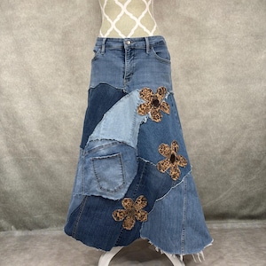 May include: A long denim skirt made from patchwork denim with a frayed hem. The skirt features three large, brown and black leopard print flowers.