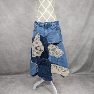 Peut inclure: Une jupe en jean avec un design patchwork en dentelle et en jean. La jupe est mi-longue et a un ourlet effiloché.