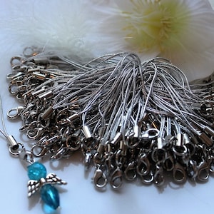 Könnte beinhalten: Eine Großpackung silberner Handy-Anhänger aus Metall mit einem blauen und silbernen Engelsanhänger, der an einem der Schnüre befestigt ist.