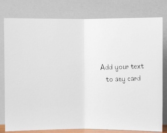 Puede incluir: Una tarjeta de felicitación abierta con páginas blancas en blanco, lista para personalizar. El texto "Add your text to any card" está escrito en escritura negra en la página derecha. La tarjeta descansa sobre una superficie de madera.