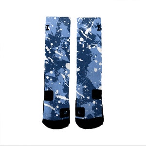 Puede incluir: Un par de calcetines azules y blancos con un dise&ntilde;o de pintura salpicada. Los calcetines tienen un logotipo negro en el lateral.