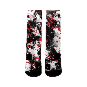 May include: A pair of black and white socks with red paint splatters. The socks have a black and white abstract design.