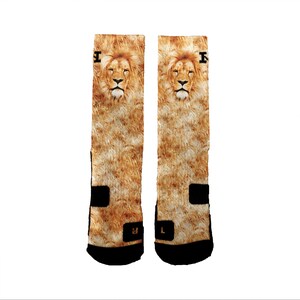 May include: A pair of brown and black socks with a lion face print. The socks have a black band around the top with the letter "I" in white.