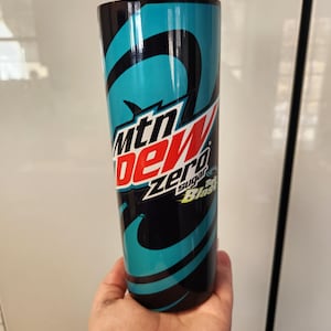 May include: A black and blue tall cup with a swirl design. The cup has a white and red logo that says "Mountain Dew Zero Sugar Baja Blast".