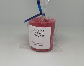 May include: A red votive candle in a clear plastic bag with a blue ribbon. The candle has a white label that reads "J. Lynn's Candle Company" and "Hand Poured in Ohio" with the website "jlynnscandles.com".