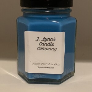 May include: A blue glass candle jar with a black lid. The label reads "J. Lynn's Candle Company" and "Hand Poured in Ohio" with the website "jlynncandleco.com".