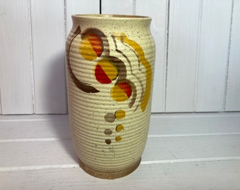 May include: A white ceramic vase with a speckled texture and a geometric design in shades of brown, yellow, and red.