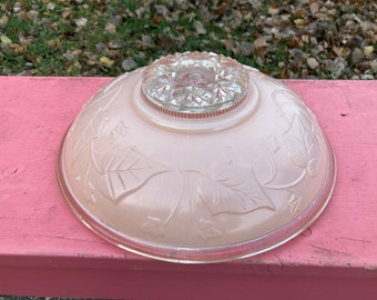 May include: A pink glass ceiling light fixture with a clear glass center piece and a floral design.
