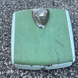 Könnte beinhalten: Vintage Badezimmerwaage in Grün und Weiß mit einem Chrom-Akzent. Die Waage hat ein rundes Zifferblatt und einen Knopf an der Unterseite.