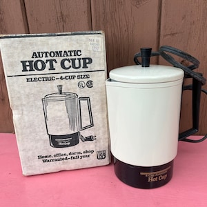 Può includere: Una macchina per il caffè elettrica automatica bianca da 4 tazze con un cavo nero e una base nera. La scatola mostra il nome del prodotto, "Automatic Hot Cup", e il testo "Electric-4-cup size".