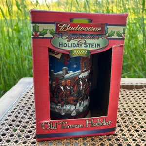 Può includere: Una scatola rossa con un design bianco e blu Budweiser Clydesdales Holiday Stein 2003 Old Towne Holiday. Lo stein presenta una scena invernale con una carrozza trainata da cavalli e un villaggio innevato.