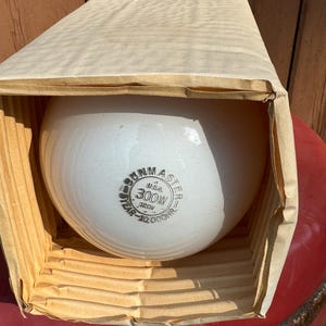 May include: A white ceramic light bulb with a black and red label that reads "Sunmaster USA 300W 120V 10,000 Hour" in a cardboard box.