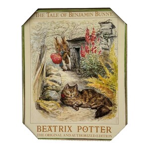 Pode incluir: Ilustração emoldurada de "The Tale of Benjamin Bunny" de Beatrix Potter. A imagem mostra dois coelhos com uma maçã, um gato dormindo e um muro de pedra. O texto "BEATRIX POTTER" e "THE ORIGINAL AND AUTHORIZED EDITION" são visíveis.